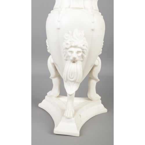 88 - A Parian ware urn featuring lion mask decoration and raised on lion paw feet. Approx. height 23cm.