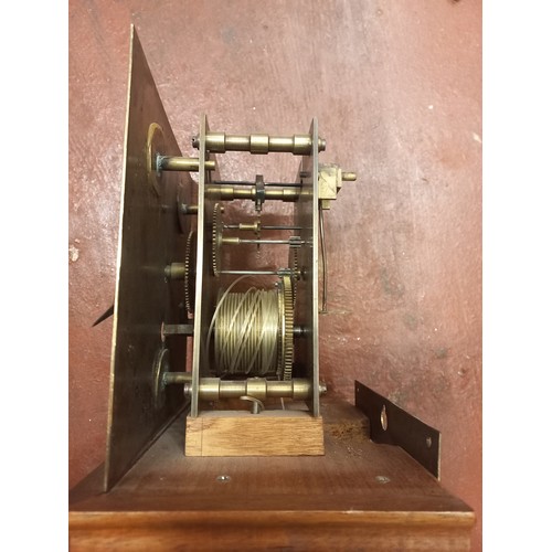 179 - An early 20th century wall clock with wooden body and brass face with roman numeral markers.