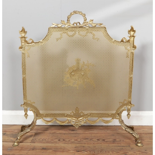 278 - A Louis XVI style gilt brass fire screen, adorned with scrolling foliage, ribbon and bagpipe decorat... 