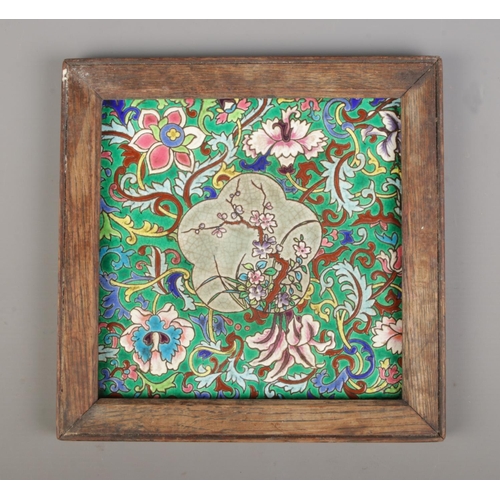 40 - A Longwy style ceramic tile with enamelled foliate decoration. In wooden frame. Tile size 20cm x 20c... 