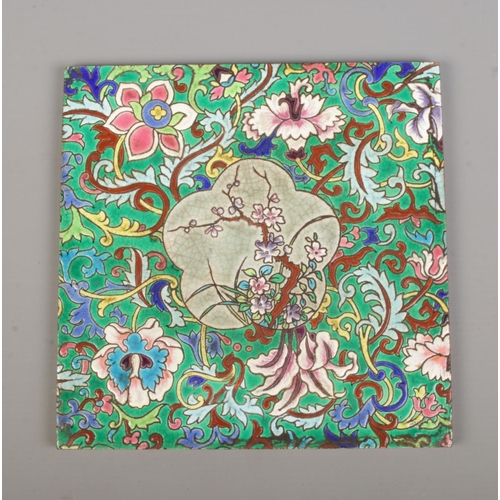 40 - A Longwy style ceramic tile with enamelled foliate decoration. In wooden frame. Tile size 20cm x 20c... 