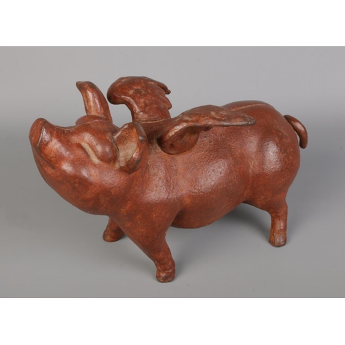 59 - A cast metal flying piggy bank, painted in a dark reddish-brown, joined with screws and featuring a ... 