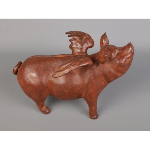 59 - A cast metal flying piggy bank, painted in a dark reddish-brown, joined with screws and featuring a ... 