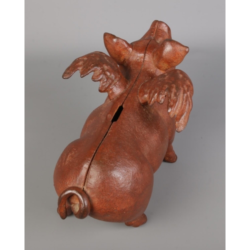 59 - A cast metal flying piggy bank, painted in a dark reddish-brown, joined with screws and featuring a ... 