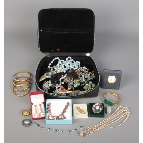 76 - A black dressing case contains vintage boxed and loose jewellery, including necklaces, a table clock... 