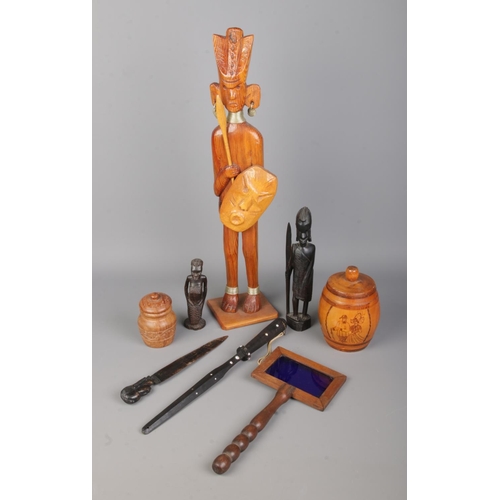 81 - A collection of carved tribal figures and assorted treen to include letter openers and small storage... 