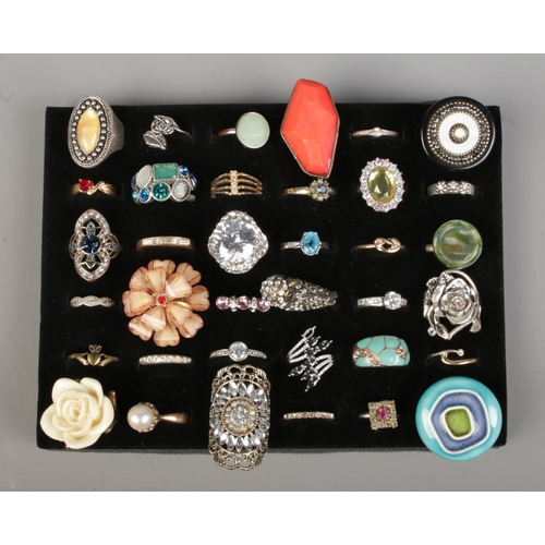 94 - A tray of thirty-six dress rings, to include polished stone, floral and claddagh examples.