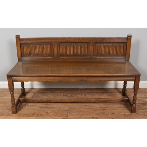 483 - An oak carved bench with linen fold design panels