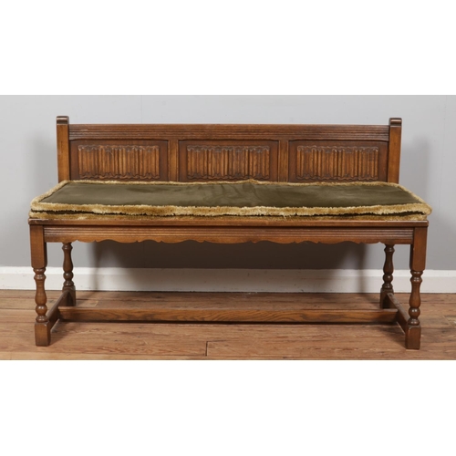 483 - An oak carved bench with linen fold design panels