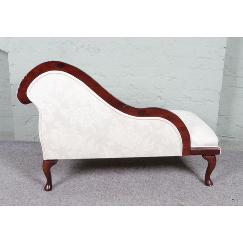 535 - A vintage chaise lounge with a wooden frame and cream upholstery. It features a curved backrest on o... 