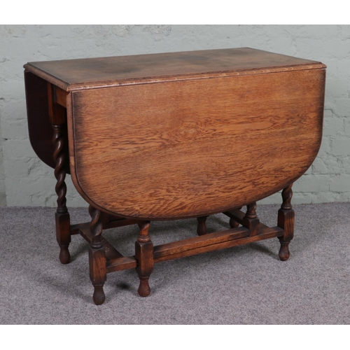 510 - An oak drop leaf gate leg table, with barley twist supports. Height: 74cm, Width (extended): 136cm, ... 