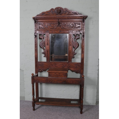 511 - An extensively carved oak hall stand. Featuring central bevel edged mirror and storage box situated ... 