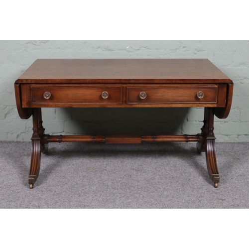 514 - A Regency style mahogany sofa table, with two lower drawers and twin stretcher. Raised on casters. H... 