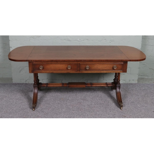 514 - A Regency style mahogany sofa table, with two lower drawers and twin stretcher. Raised on casters. H... 