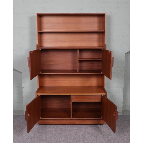 518 - A tall teak unit, raised on casters. Consists of two open bookcase shelves above two sets of cupboar... 