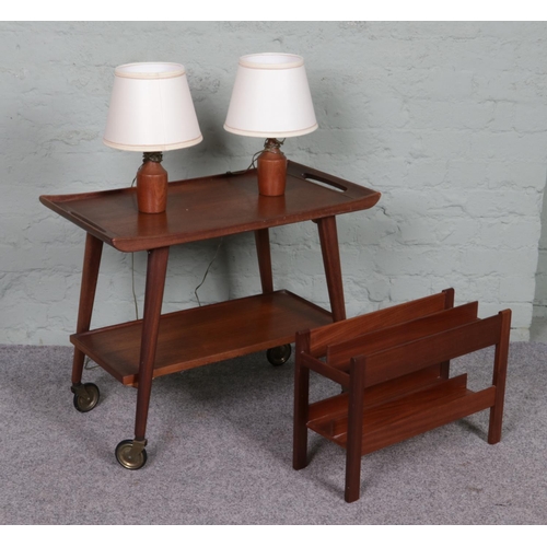 528 - A Teak two tier drinks trolley with a pair of teak bedside lamps and similar magazine rack.