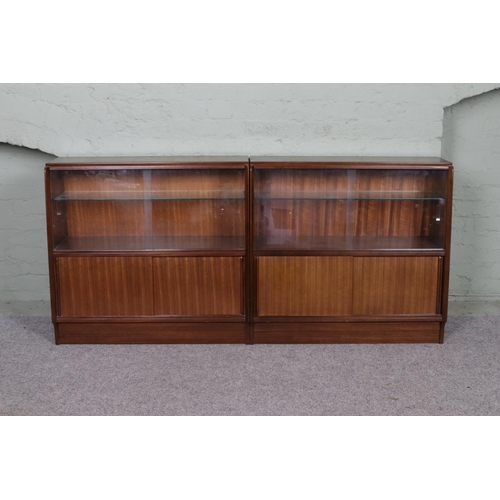 532 - A pair of teak mid century book cases with sliding glass doors over sliding wooden doors.