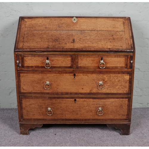 554 - A Georgian oak bureau banded with mahogany on bracket feet