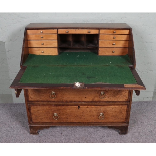 554 - A Georgian oak bureau banded with mahogany on bracket feet