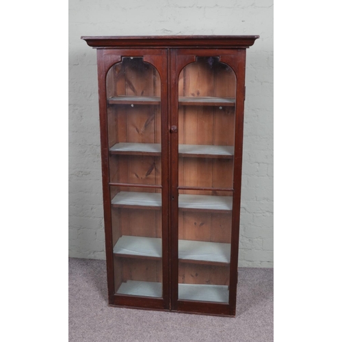 567 - A stained pine two door display cabinet, with glazed front and four interior shelves. Height: 153cm,... 