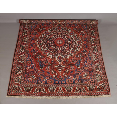 128 - A large antique red ground wool rug with central medallion and floral border. 335cm x 245cm.