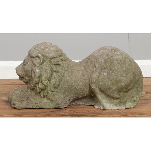 134 - A pair of reconstituted stone crouching lions. Length 59cm.