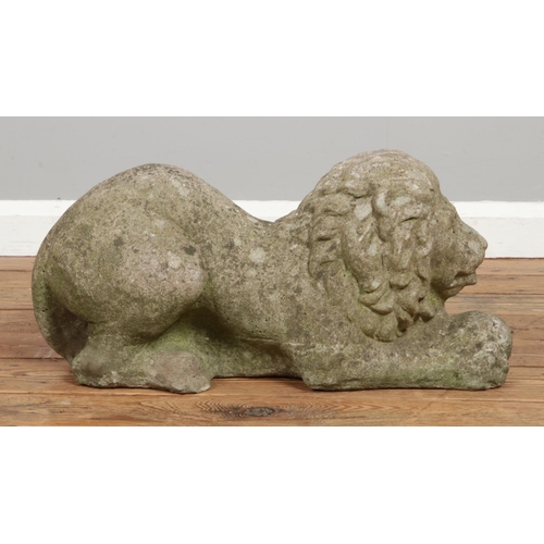 134 - A pair of reconstituted stone crouching lions. Length 59cm.