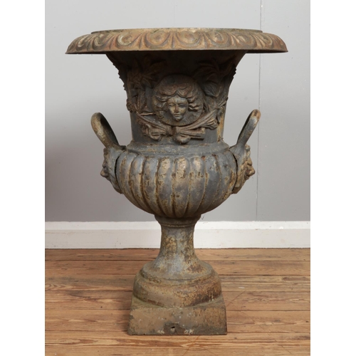 136 - A pair of Victorian cast iron garden urns. Having mask decoration and twin lion mask handles. Height... 