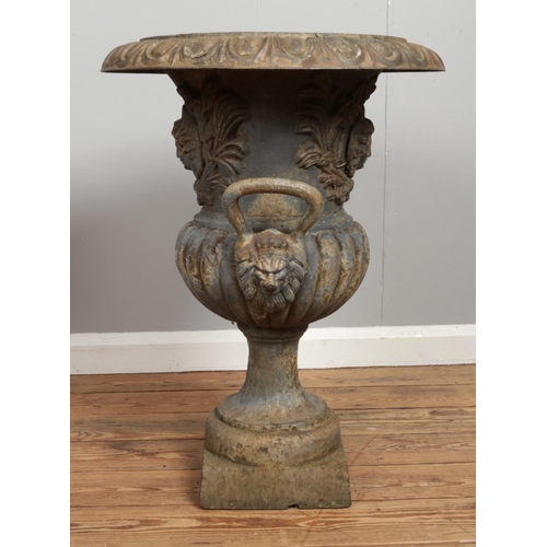 136 - A pair of Victorian cast iron garden urns. Having mask decoration and twin lion mask handles. Height... 