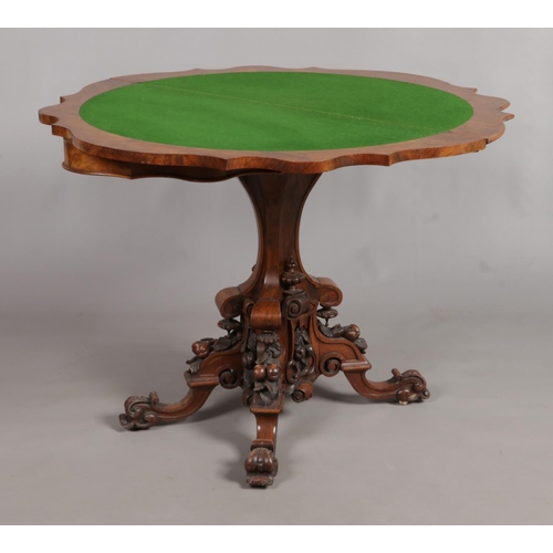 152 - A Victorian walnut fold over games table. Raised on extensively carved splayed based.