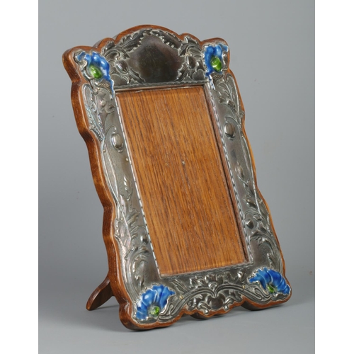 70 - An Art Nouveau silver mounted easel photograph frame. Decorated in relief with flowers and having en... 