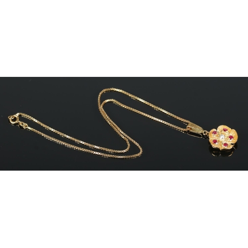 95 - An 18ct yellow gold floral pendant set with a single diamond and five ruby stones. On 18ct yellow go... 