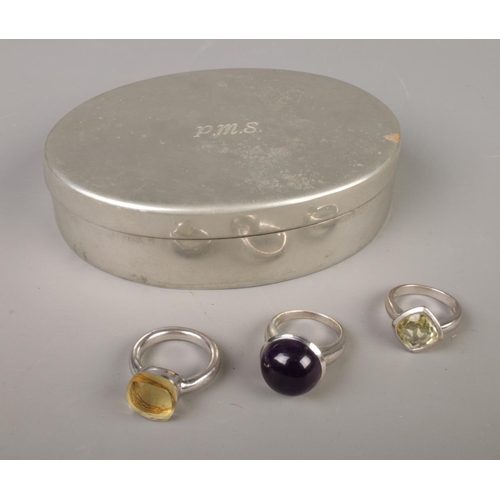 412 - A collection of three silver rings including an amethyst coloured stone variety and two lemon citrin... 