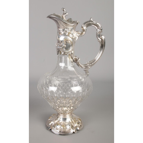 488 - A Continental white metal mounted claret jug with Rococo style decoration. Approx. height 31cm.