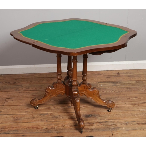 527 - A walnut inlaid fold over card table raised on four turned supports and scroll carved legs. Approx. ... 