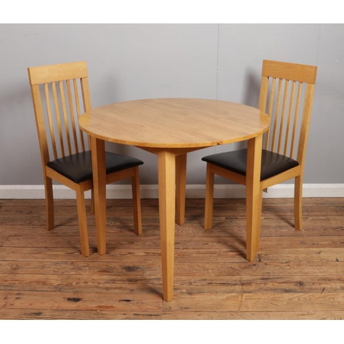 532 - A Malaysian hardwood circular dining table with two slat back chairs.