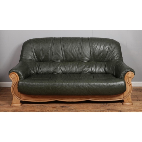 534 - A green leather sofa and matching arm chair. With wooden frame and faux bergere sides.