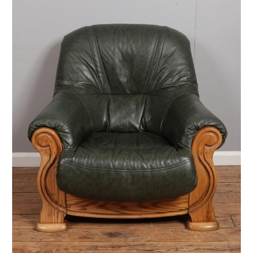 534 - A green leather sofa and matching arm chair. With wooden frame and faux bergere sides.