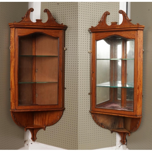 541 - A pair of Georgian style satinwood hanging corner cabinets. With twin swan neck pediments, one with ... 