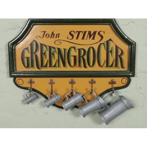 385 - A vintage John Stims Greengrocer advertising sign featuring five graduated tankards on hooks and dec... 