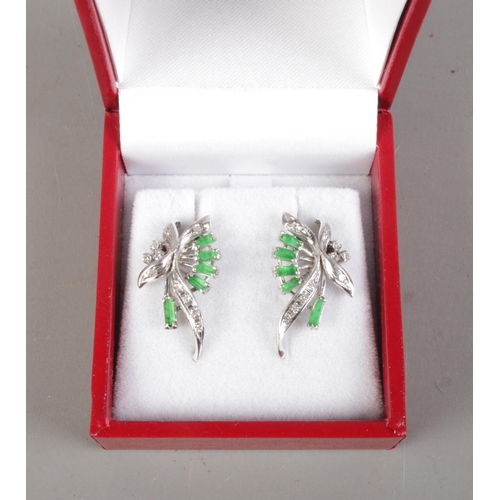 532 - A pair of white metal emerald and diamond earrings.