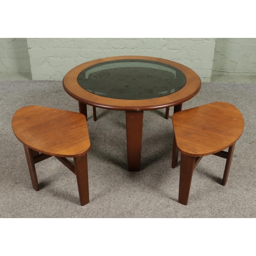 676 - A mid century smoked glass top teak coffee table with three smaller nesting tables. Height 44cm, Dia... 