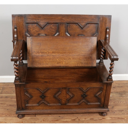 504 - An Edwardian oak Monk's bench featuring a hinged seat that provides storage beneath. It is supported... 