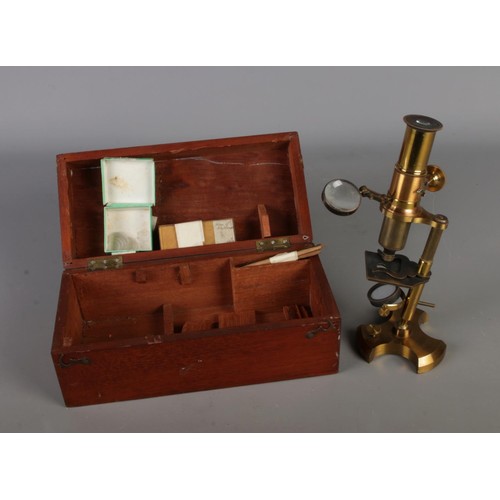 29 - An antique brass scholar's microscope, with accessories and original walnut wooden case.