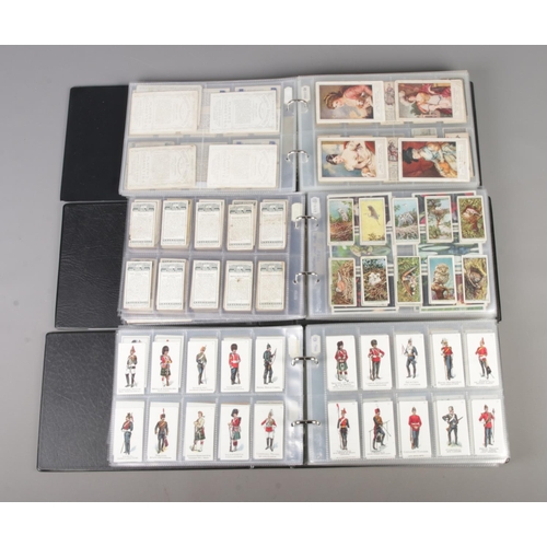 47 - Three albums of part sets of Cigarette and collectors cards, surrounding the themes of Royalty, Mili... 