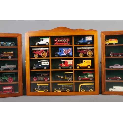 51 - Three display cabinets with glazed fronts housing model die-cast vehicles. Includes examples from Le... 