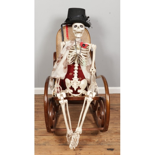 534 - A bentwood frame bergere rocking chair, accompanied by a model skeleton.