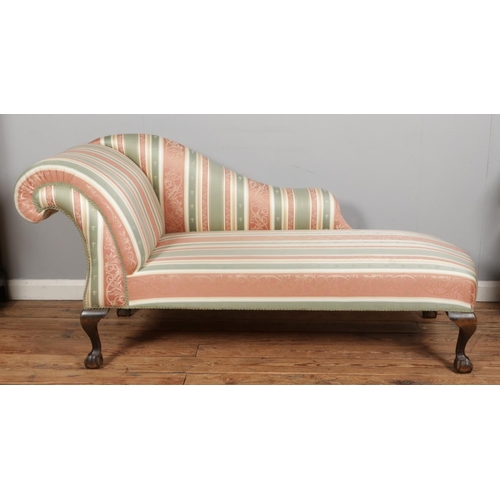 550 - A Twentieth Century chaise lounge, in striped fabric upholstery raised on mahogany ball and claw fee... 