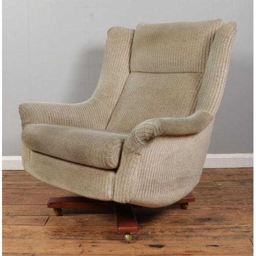 551 - A Mid-Century G-Plan upholstered swivel chain on four point base, raised on casters.