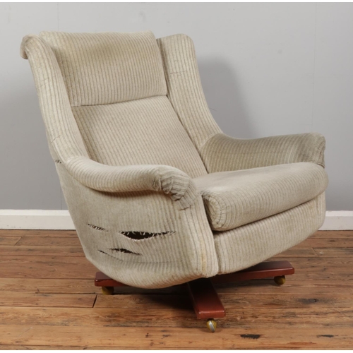 551 - A Mid-Century G-Plan upholstered swivel chain on four point base, raised on casters.